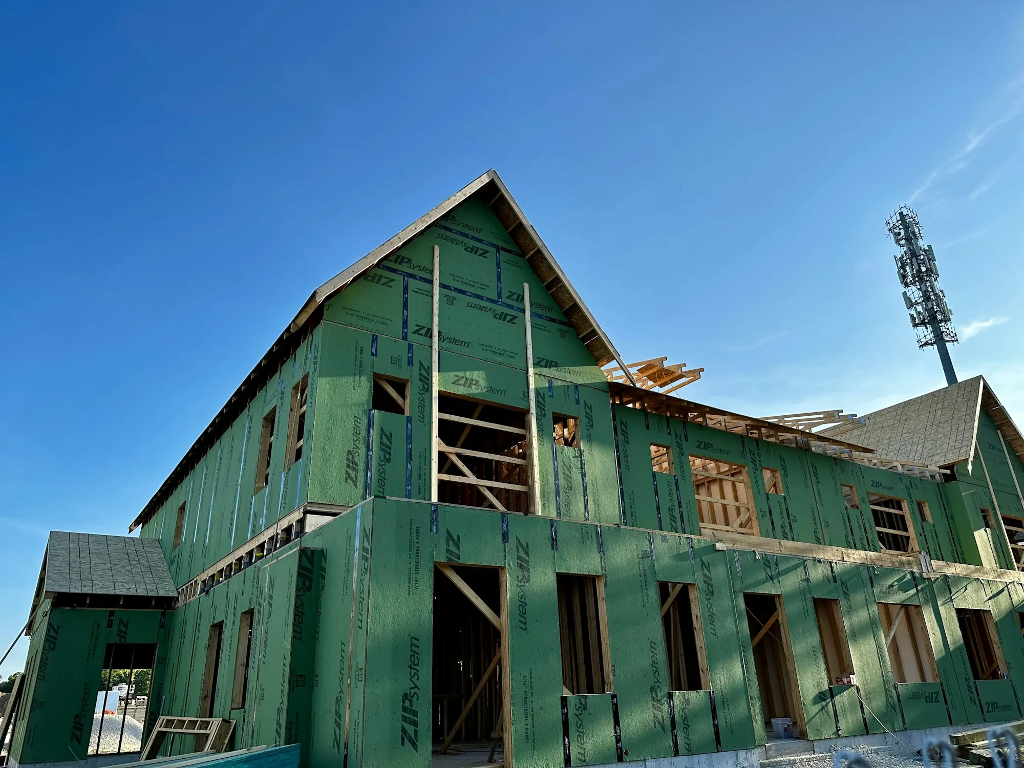 Two-story house sheathed in green panels during construction