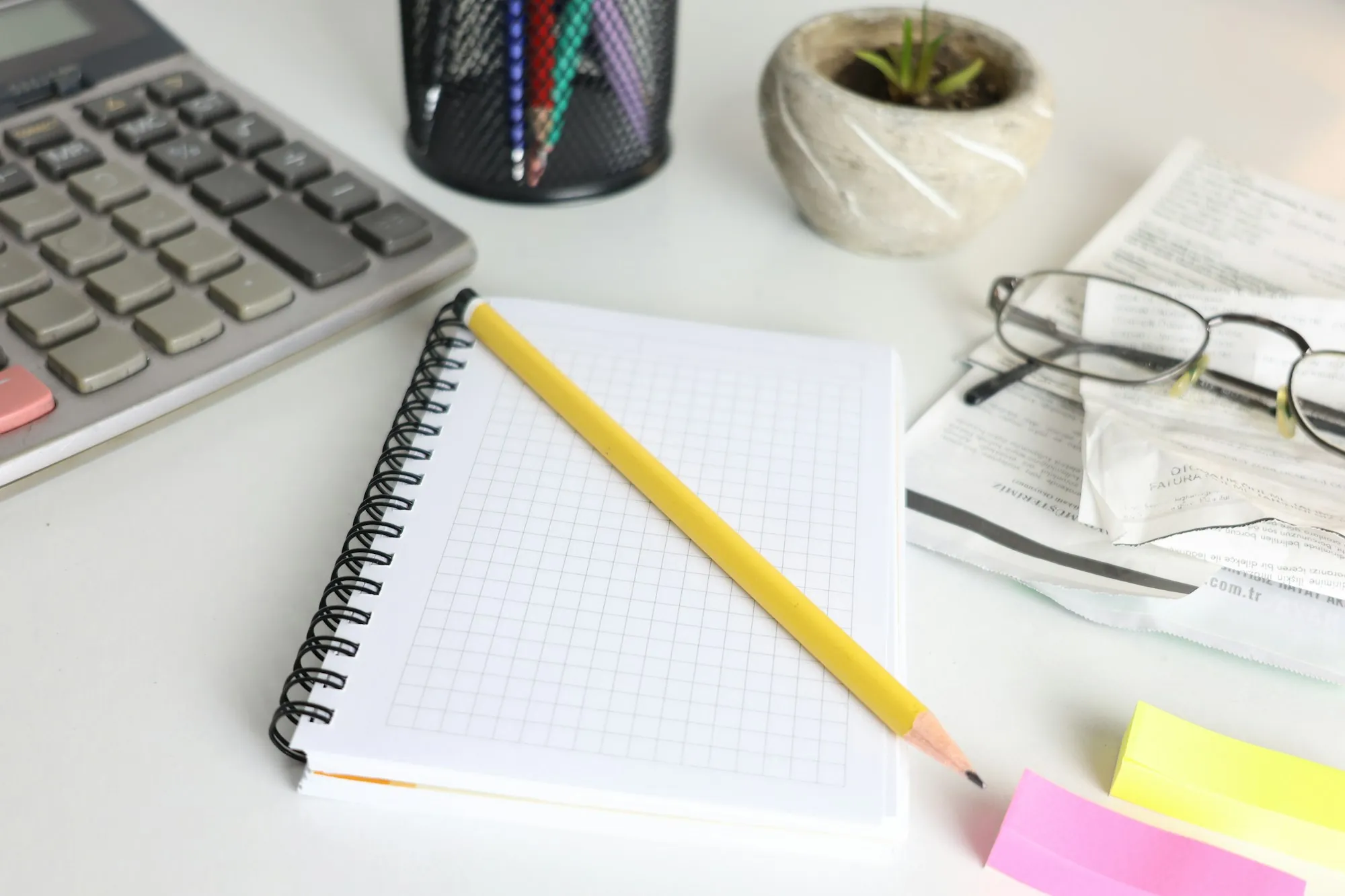 Notebook, pencil and calculator on a white desk